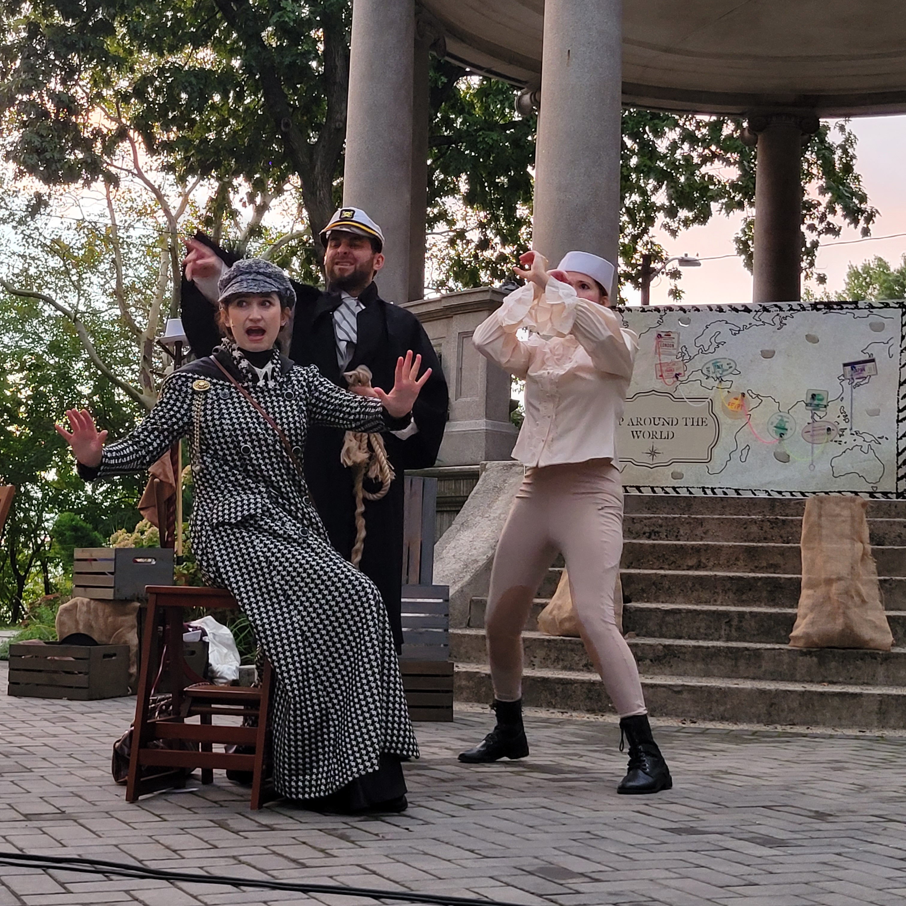 Three actors performing on a stage outdoors