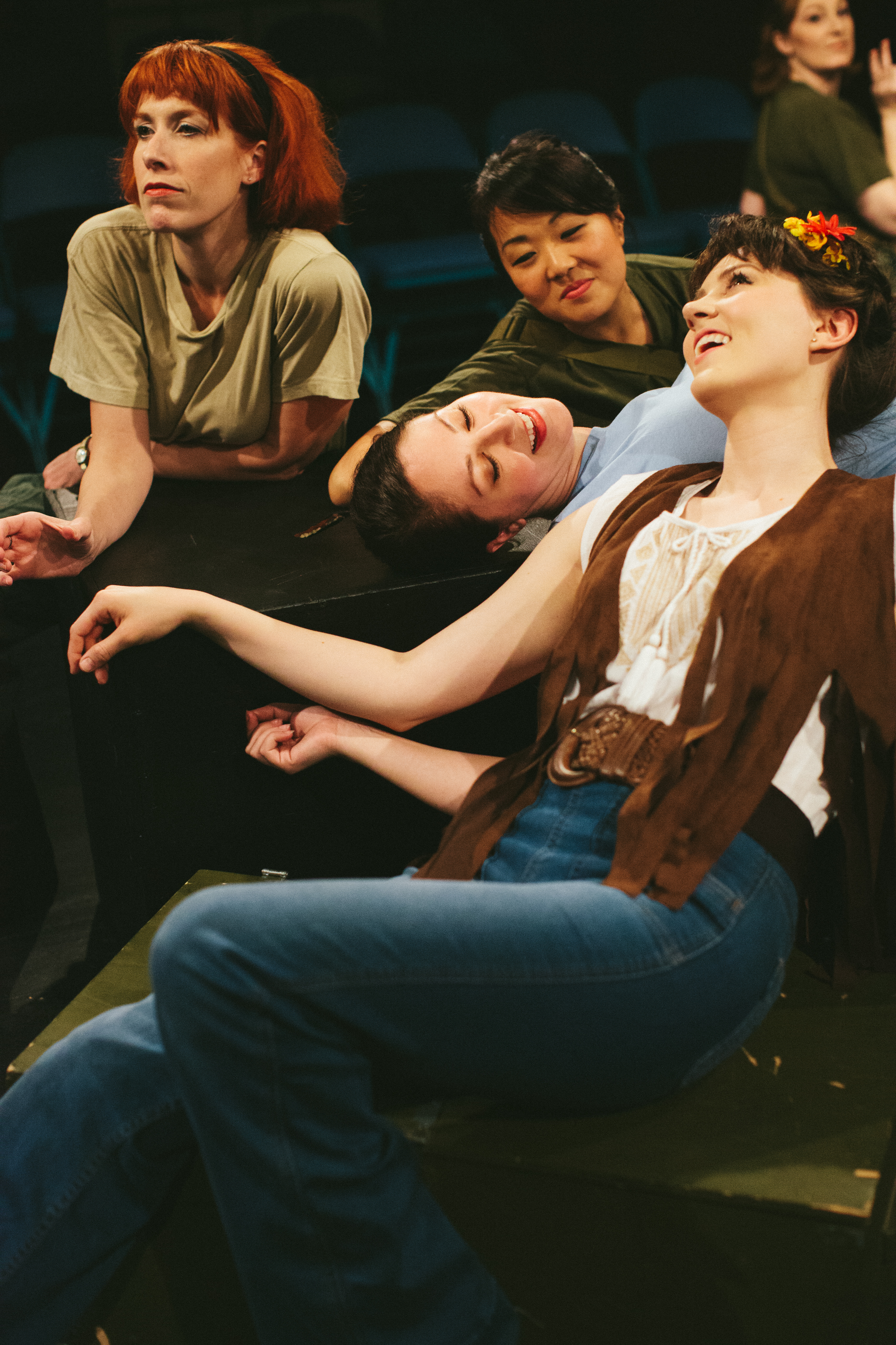 Several women rest on top of boxes onstage