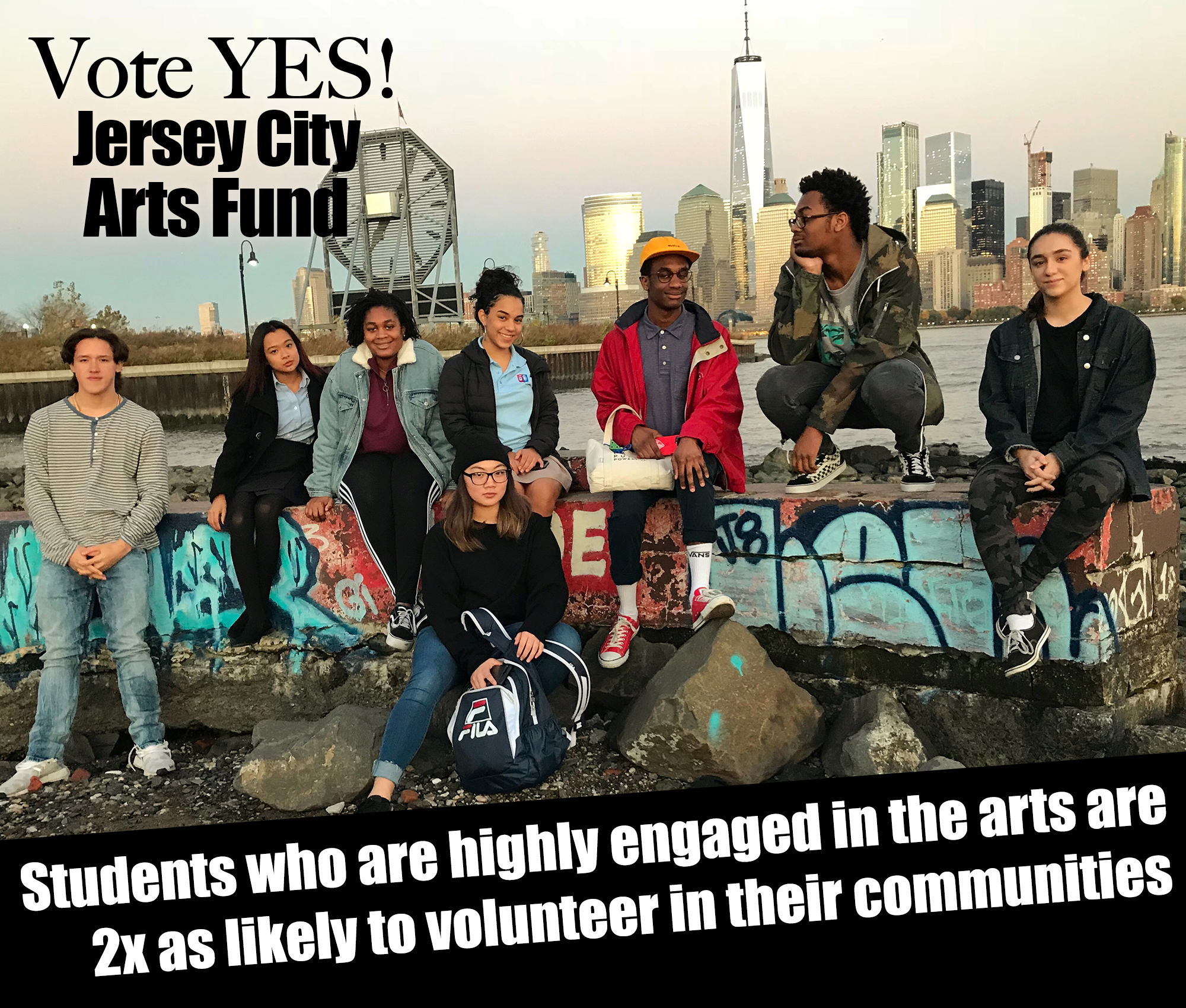 A group of eight ethnically diverse high school-aged students are smiling at the camera with a city skyline behind them. The words "Vote yes! Jersey City Arts Fund" and "Students who are highly engaged in the arts are 2x as likely to volunteer in their communities" are seen on the image in white letting.